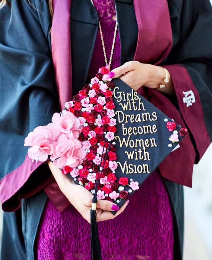 Graduate holding a decorated cap with inspiring quote at college graduation.
