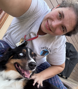 Happy woman with a dog outdoors, smiling and enjoying pet care time.