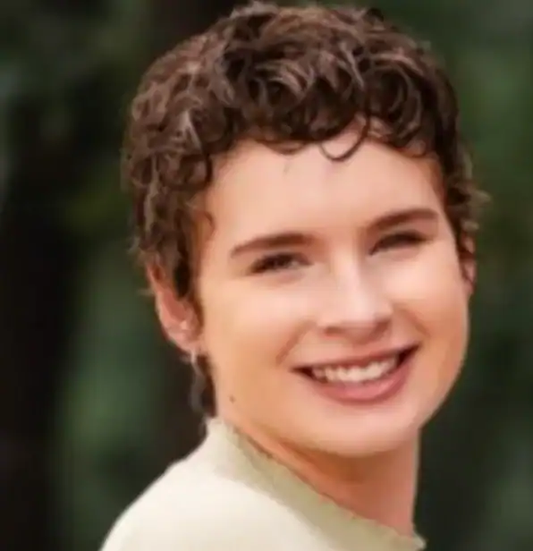 Smiling young woman with short curly hair outdoors.