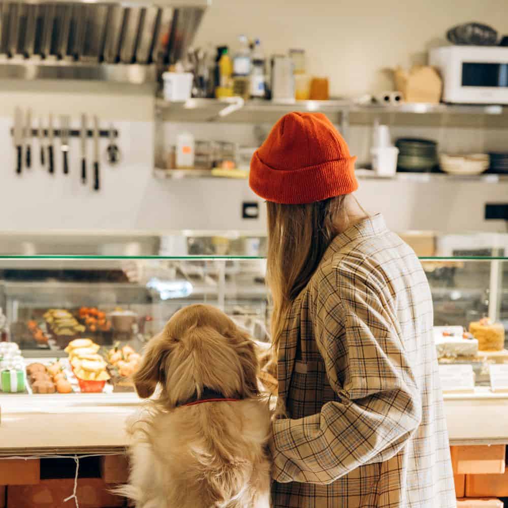 Woman with a dog at a bakery counter in a cozy shop setting.